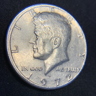1972 Kennedy half dollar off-center strike showing partial design with blank copper-nickel planchet crescent and full date 1972 visible